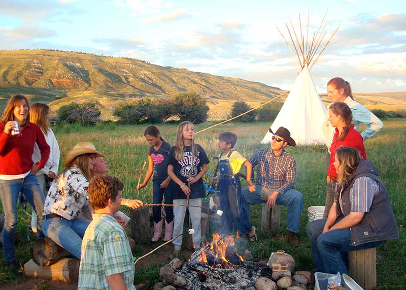 Family roasting marshmallows over a campfire at an American dude ranch in Colorado Family roasting marshmallows over a campfire at an American dude ranch in Colorado