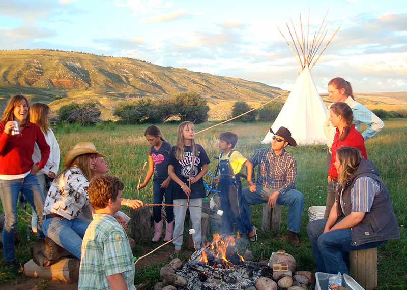 Family roasting marshmallows over a campfire at an American dude ranch in Colorado